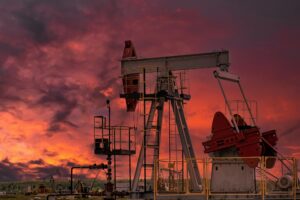 Oil drill rig and pump jack at sunset background.